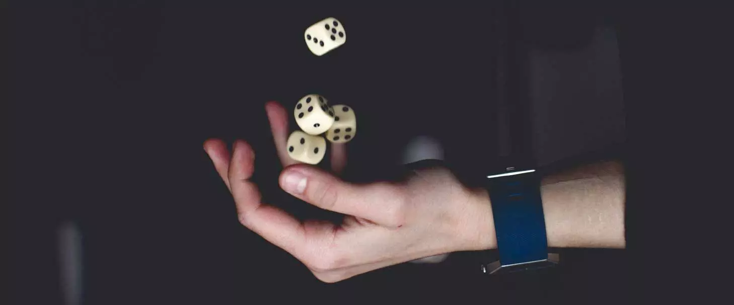 An image of a hand tossing four dice in the air to represent an action built on risk