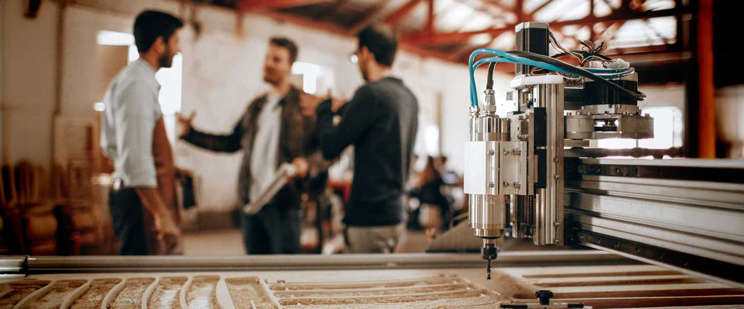 An image of three men discussing how to enhance profitability while standing in a CNC shop